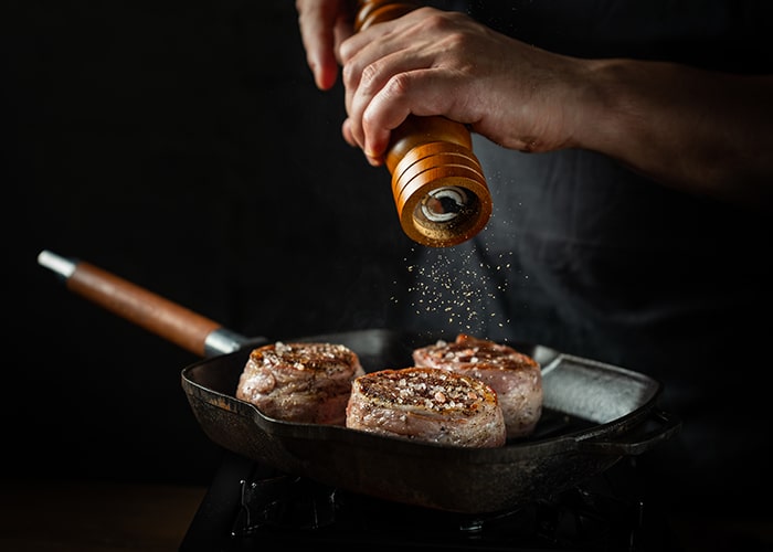 dieses Bild zeigt, wie Fleisch mit Knoblauch-Pfeffer gewürzt wird